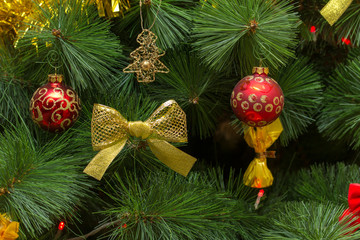 Christmas tree in a rich red and gold outfit with balls and a bow
