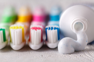 squeezing toothpaste from tube on modern toothbrush close up