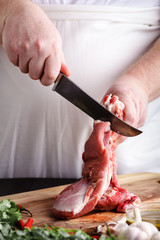 Butcher cutting lamb meat on kitchen