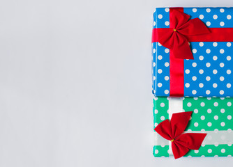Gift boxes with red and white ribbon and red bows, in blue and green packaging. Copy space.