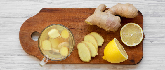 Homemade ginger tea with lemon on wooden board over white wooden background, overhead view. Flat lay, from above.