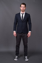 Young handsome bearded businessman against gray background