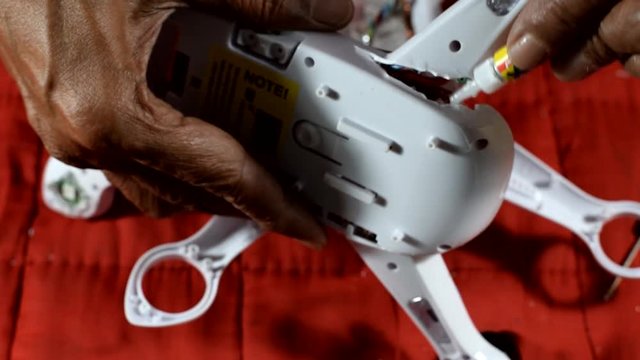 Inventive, resourceful Old man repairing broken quad-copter that he accidentally crash