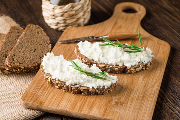 Whole grain bagels with cream cheese on wooden board, selective focus