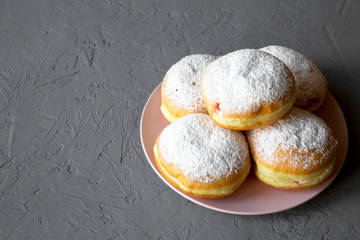Homemade sweet donuts with powdered sugar on concrete background, side view. Copy space.