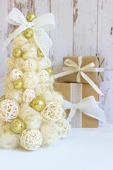 Fototapeta na wymiar New Year, Christmas background, rustic style. Festive Christmas tree in gold on white wood background and craft boxes tied with satin ribbons. Beautiful Christmas tree with Golden balls, frame of whit