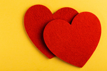 Two red felt heart on bright yellow background
