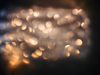 Blurred background lights. Abstract defocused gold, white, red and yellow glitters texture on black background. Shining glowing snow effects