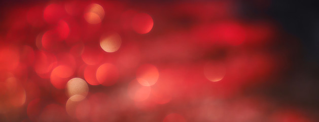 Blurred background lights. Abstract defocused gold, white, red and yellow glitters texture on black background. Shining glowing snow effects