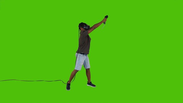 Enthusiastic First person shooting with guns in a VR video game by a young man over a green screen, casual look, long shot.