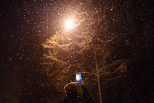 Woman taking a photo of falling snow