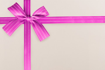 Pink gift ribbon on a white textured pattern in background. Gift box wrapping concept.