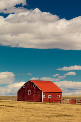 Red barn in field with puffy clouds in remote Oklahoma