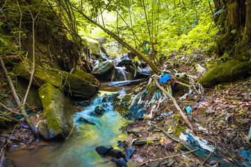Beautiful forest stream highly polluted with waste
