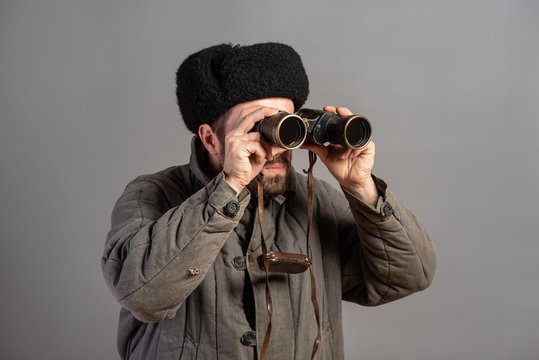 Soviet scout with a binocular keeps track of the situation, studio shot. Great Patriotic War theme