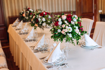 beautifully decorated table for wedding guests. chic bouquets of roses and peonies in transparent vases