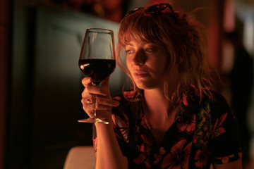 Beautiful ginger girl drinking a glass of red wine near a fire pit