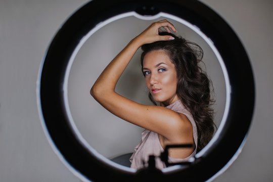 Young attractive woman posing behind the selfie lamp