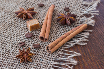 Fototapeta na wymiar Star anise, cinnamon sticks, sugar cube and coffee grains on sackcloth