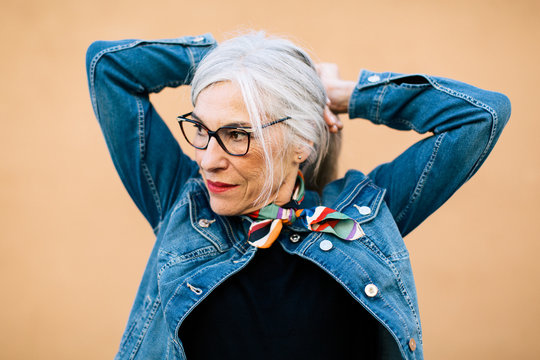 Portrait of a cool senior woman with grey long hair wearing denim clothes.