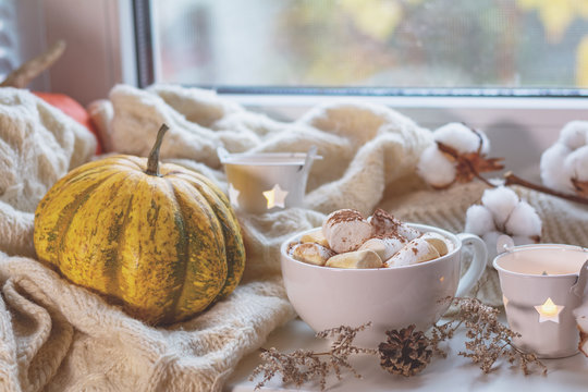 Cup of coffee with marshmallow on windowsill, cozy home concept