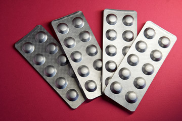 Tablets in four metallic blisters on a pink background