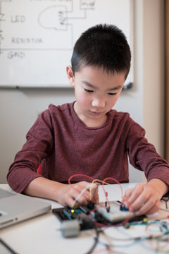 Boy working on an electronic DIY kit at home