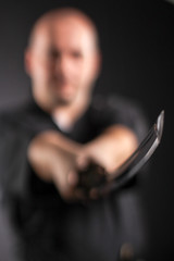 Samurai master training with sword in studio on black.