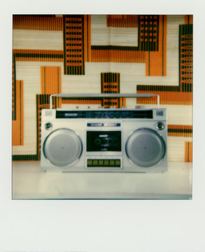 Polaroid scan of a ghetto blaster in front of 1980s fabric.