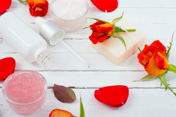beauty product samples with roses on white wooden, soft light