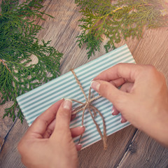 Christmas, new year concept. Hands with Gift for holidays. Gifts, different winter plants on wood background. Flat lay, top view