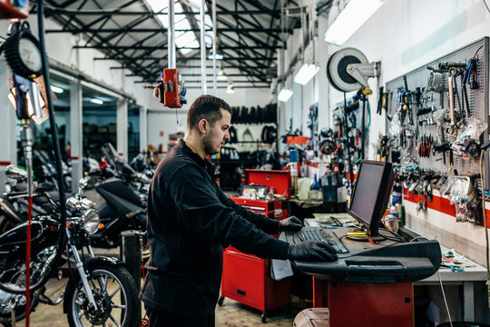 Mechanic working in computer at the motorbike workshop