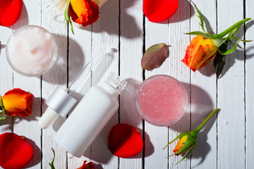 beauty product samples and roses with shade on white wooden table