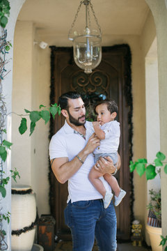 Young dad holding child outside of suburb house