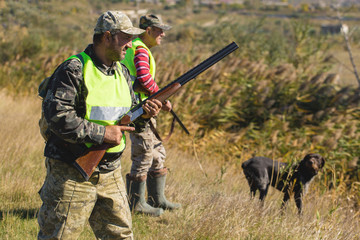 Hunters with a german drathaar and spaniel, pigeon hunting with dogs in reflective vests	