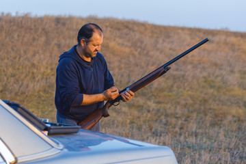 The guy shoots cartridges with a gun in nature, The hunter shoots at the target at sunset	