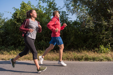 young couple jogging along a country road