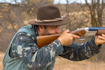 Hunter with a hat and a gun in search of prey in the steppe	