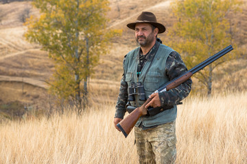 Hunter with a hat and a gun in search of prey in the steppe	