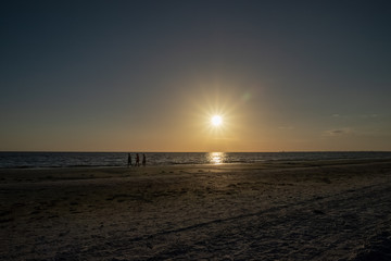 Group of women take a leisurely walk along Fort Myers Beach during sunset