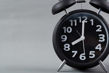 Black color vintage alarm clock, on grey background. wake up time concept.