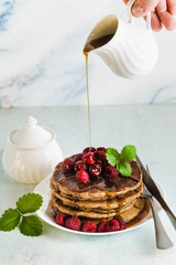 pouring maple syrup over gluten free green buckwheat pancakes with fresh berries. Delicious vegan breakfast. healthy food for the whole family. Moka pot with morning coffee