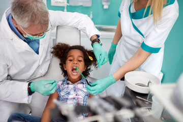 Dental assistant putting dental suction in kid's mouth