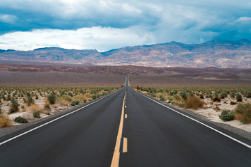 A straight road drives through the Valley of death during a rare storm