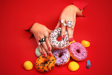 Kolorowy manicure. Kobieta trzyma w dłoniach kolorowe, lukrowane donuty - obrazy, fototapety, plakaty