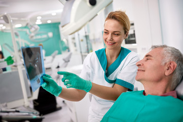 Obraz premium Male patient and female dentist looking at teeth X-ray