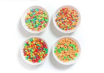 bowls of different colorful cereal on a white background. multicolored rings, balls and breakfast cereals. flat lay, top view