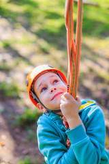 smiling boy rides a zip line. happy child on the zip line. The kid passes the rope obstacle course. vertical