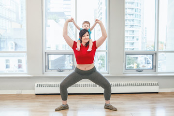 Obraz premium Young woman with child doing workout in gym class to loose baby weight. Child-friendly fitness for mothers with kids toddlers. Lifestyle concept of parent activity.