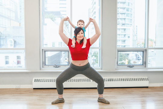 Young woman with child doing workout in gym class to loose baby weight. Child-friendly fitness for mothers with kids toddlers. Lifestyle concept of parent activity.